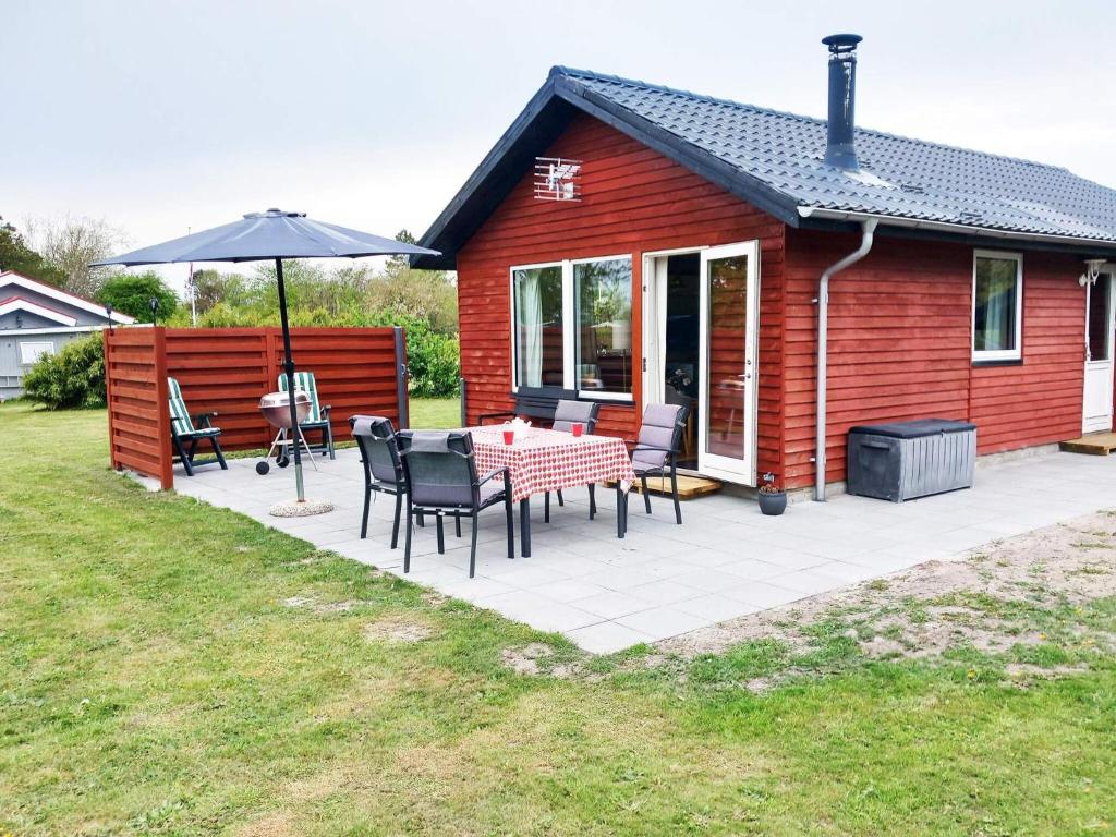 a red cabin with a table and chairs and an umbrella at 6 person holiday home in Nibe in Nibe