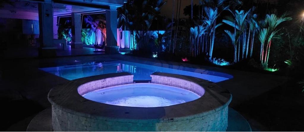 a jacuzzi tub in a backyard at night at Mansión Versace in Panama City