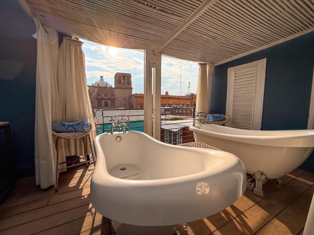 a bathroom with two tubs and a large window at La Casa del Atrio in Querétaro