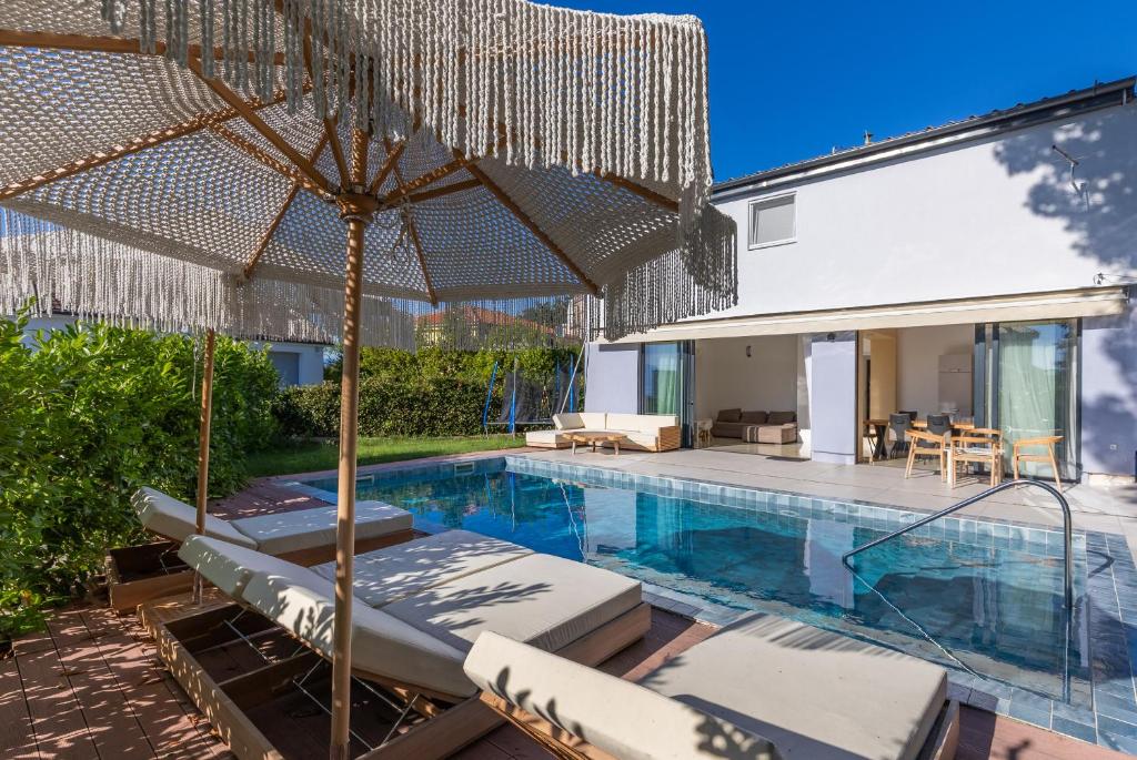 a swimming pool with chairs and an umbrella at House Serenity in Njivice