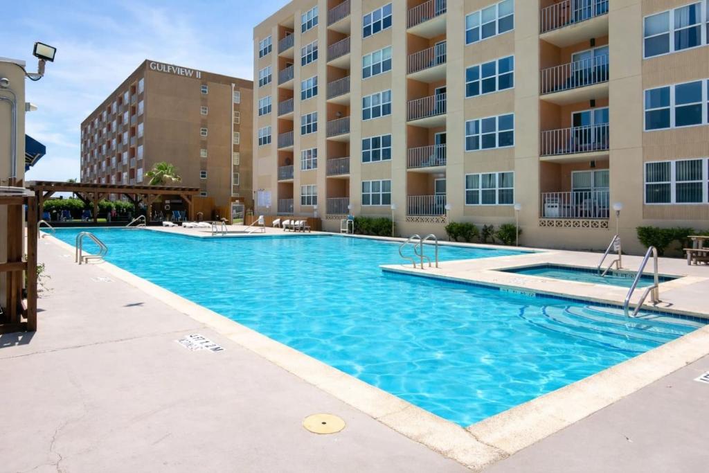 a swimming pool in front of a apartment building at EZ Beach Access Great Family Condo SpaceX view in South Padre Island
