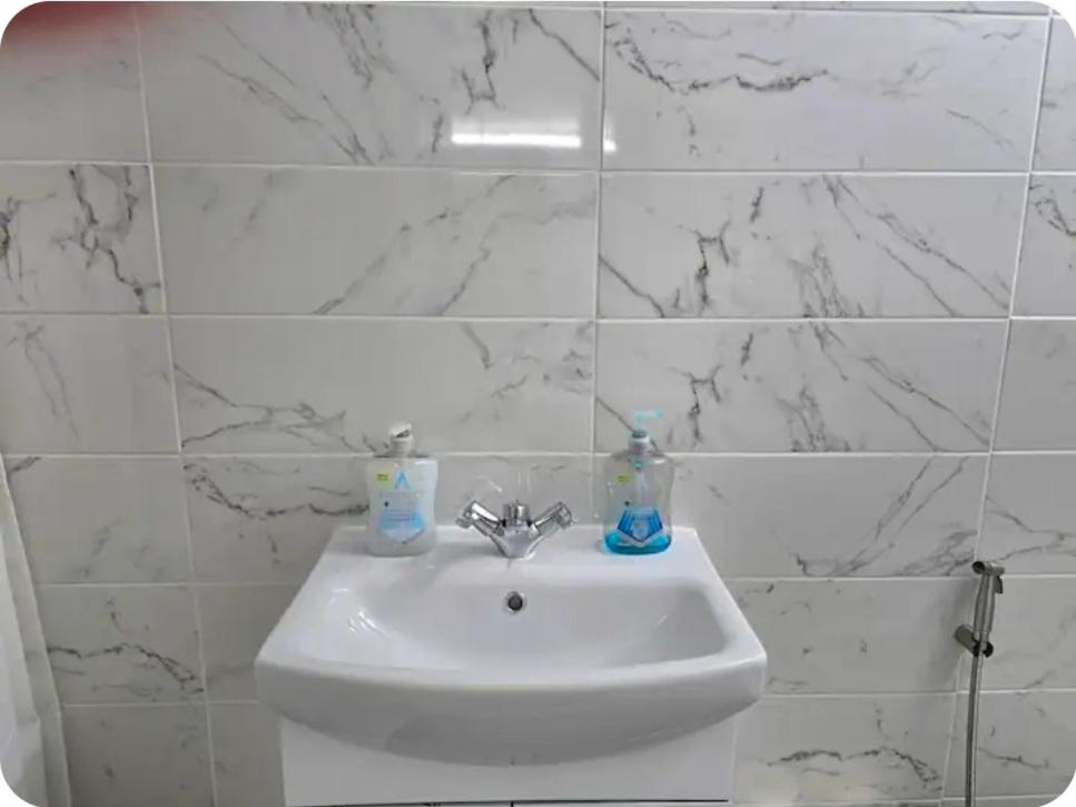 a white sink in a bathroom with marble walls at Double Room with attach Bathroom in London