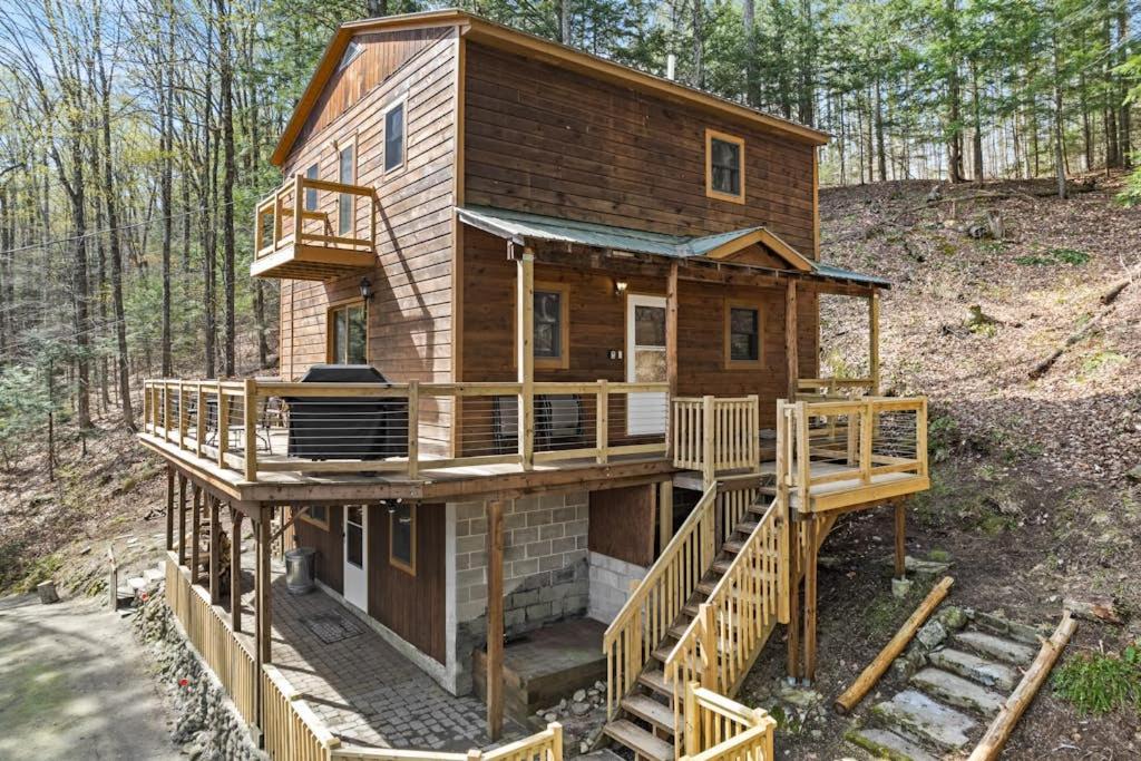 a house with a wrap around deck in the woods at River Road Treehouse Retreat in Warrensburg