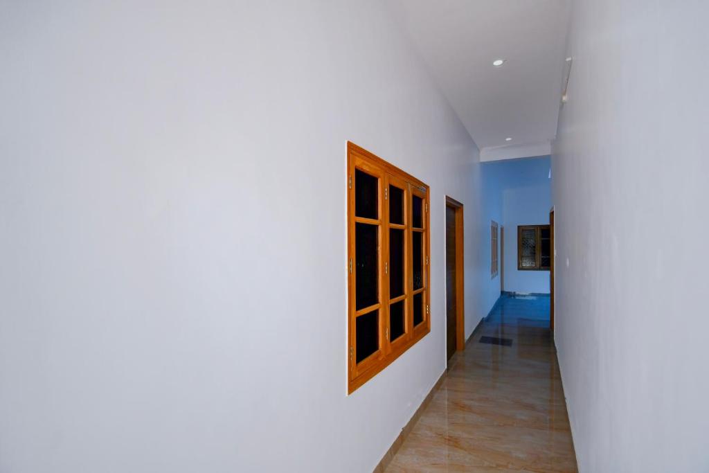 a hallway with a white wall and a wooden window at HOTEL O SAV INN in Bhauli