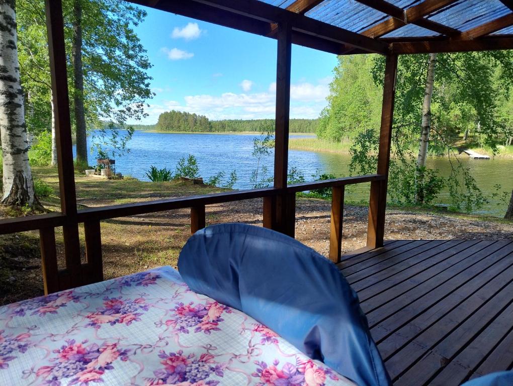a porch with a bed and a view of a lake at Lomasaaret Cottages in Villala