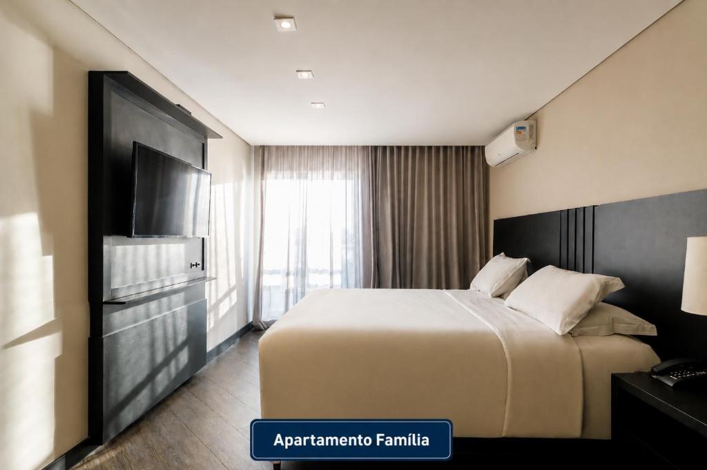 a hotel room with a bed and a flat screen tv at Slaviero Hotel Baia Norte Florianópolis in Florianópolis