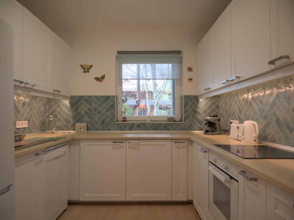 a kitchen with white cabinets and a window at Rózsa Villa Vadkerti tó in Soltvadkert