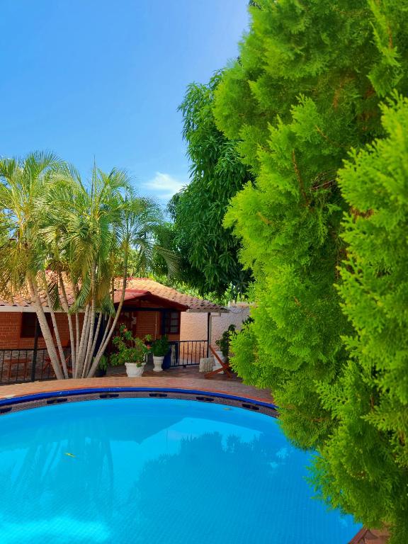 a swimming pool in front of a house with trees at Cabaña Florez in Santa Marta