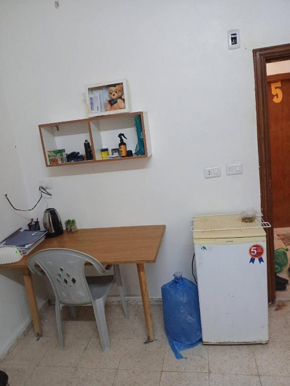 a room with a desk and a table and a refrigerator at Lovely hotel in Al Qābūţī