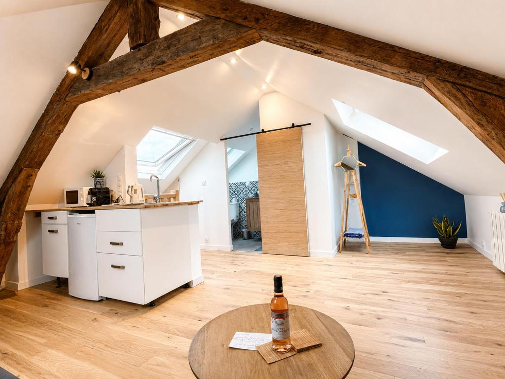 an attic kitchen with a table and a bottle of wine at Le bleu infini - vue mer, falaises, centre ville in Étretat
