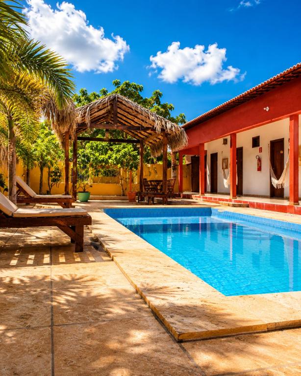 a swimming pool with a pergola next to a house at Maruá Pousada da Lagoa in Jijoca de Jericoacoara