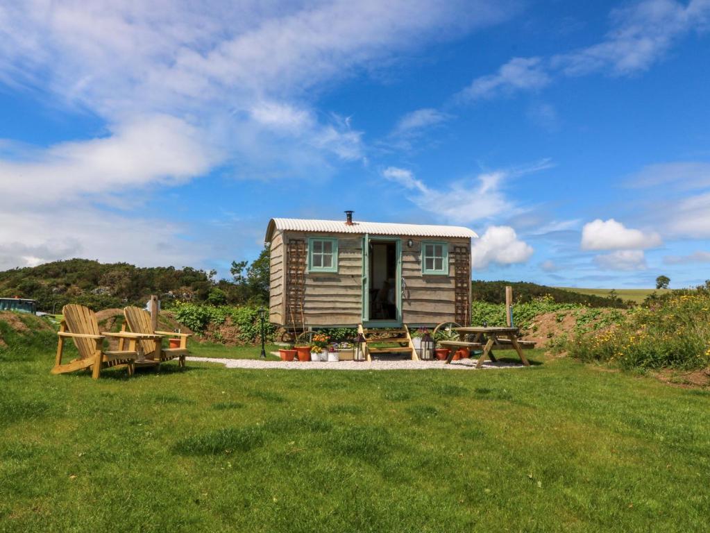 ein kleines Haus mit Picknicktisch und Bänken in der Unterkunft Cwt Bugail in Pwllheli