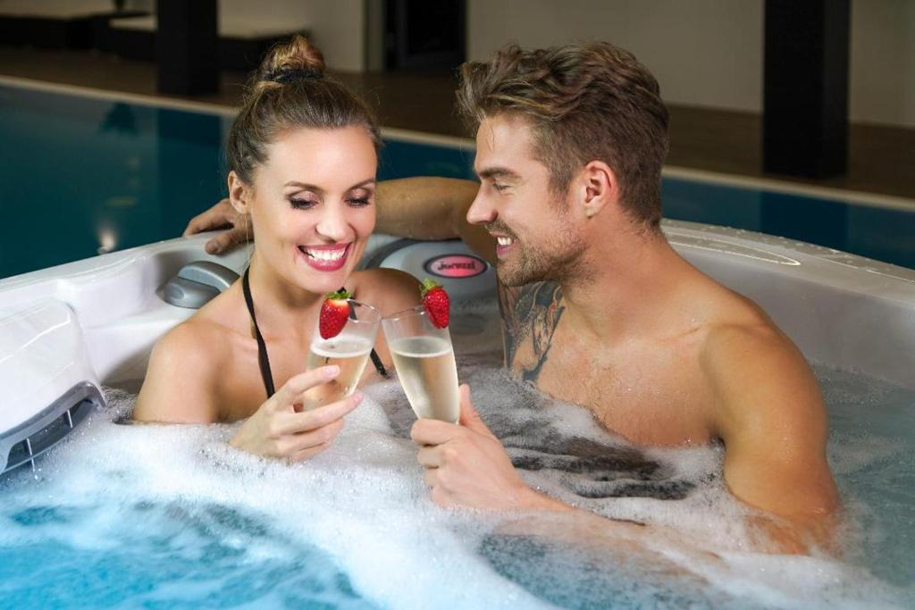a man and woman in a bathtub with champagne and strawberries at Stella APART Resort & SPA in Władysławowo