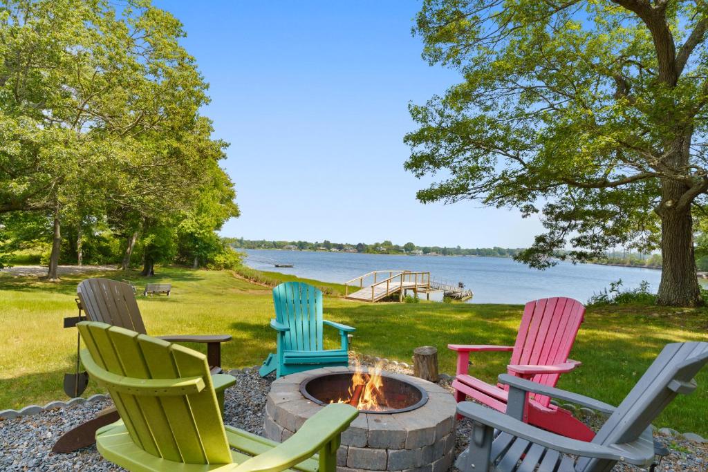 a group of chairs around a fire pit by the water at Waterfront Estate w Hot Tub, Dock & Kayaks in Stonington