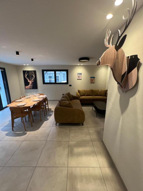 a living room with a table and a deer head on the wall at Les Loges de Sainte Anne in Saint-Michel-de-Maurienne