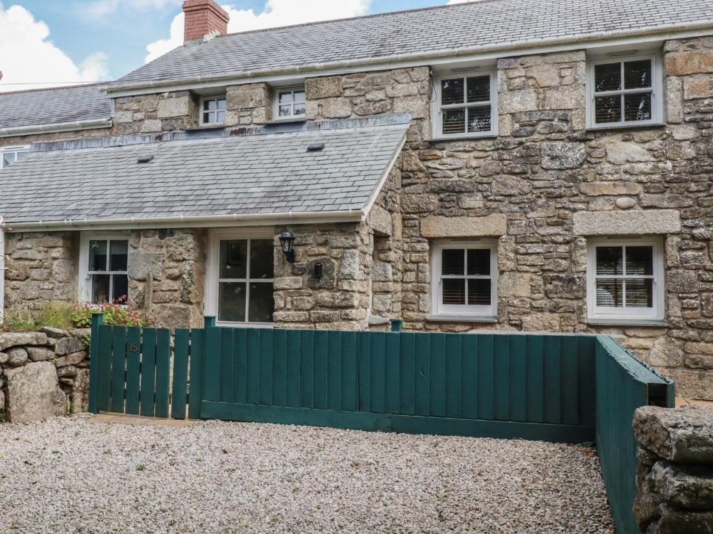 an old stone house with a green fence at 15 Boscaswell Downs in Penzance