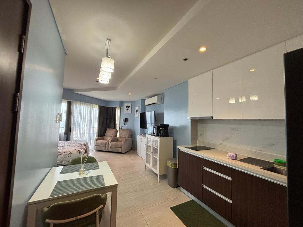 a kitchen and living room with a couch and a table at Ocean View Corner Studio Private Balcony Tambuli Tower F in Maribago