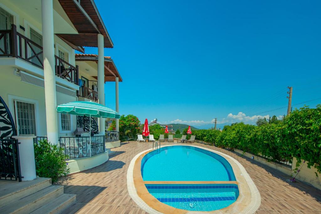 a swimming pool next to a house with an umbrella at HENNA VILLA in Fethiye