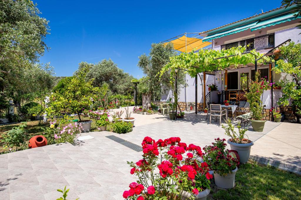 a patio with red flowers in a yard at Studios Panagiotas House Astris in Astris