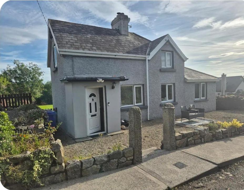 a small house with a stone fence in front of it at Cottage on the hill in Carlow