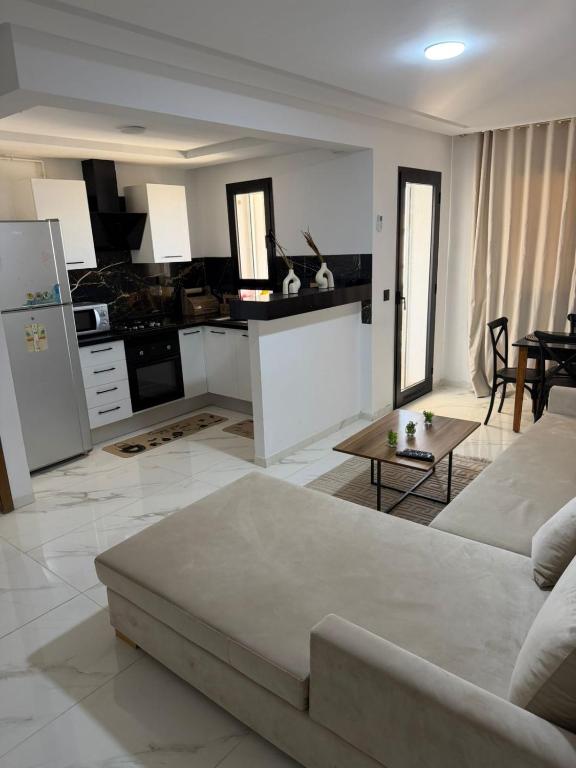 a living room with a white couch and a kitchen at Lux appartement S plus deux a hay el wahat in El Aouina Station