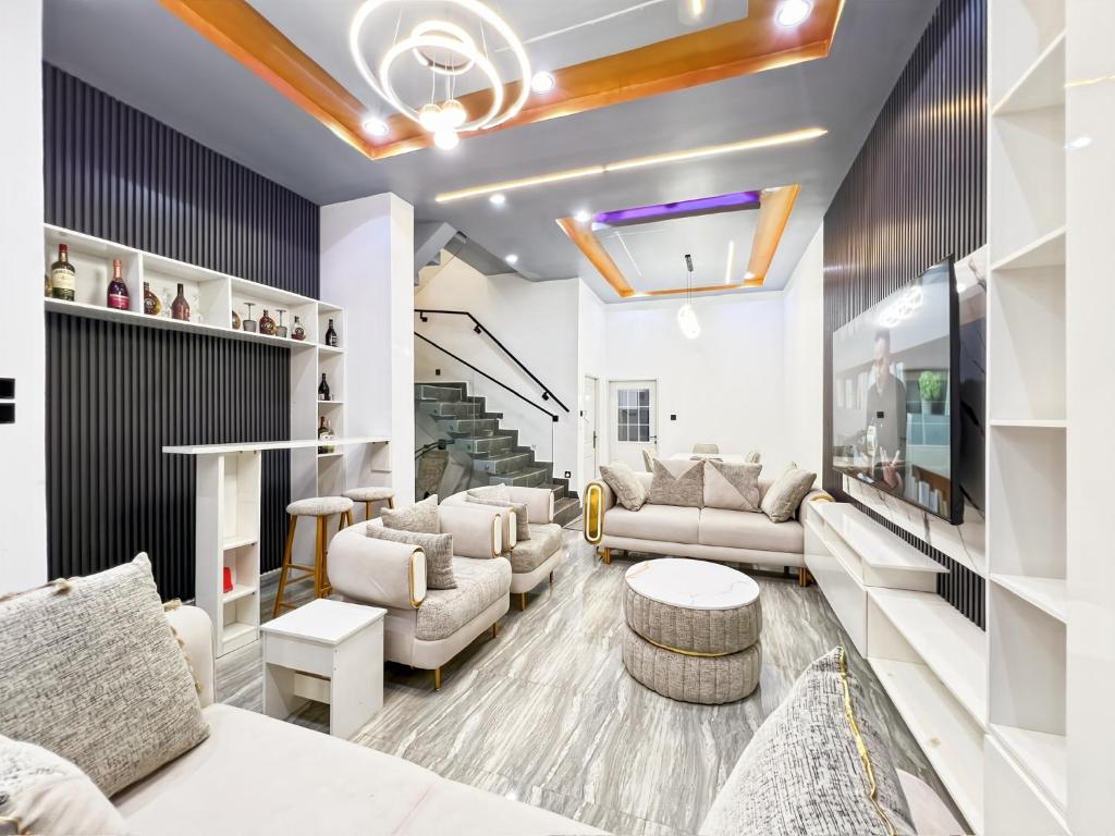 a living room with white furniture and a staircase at Domina Apartment in Kubwa