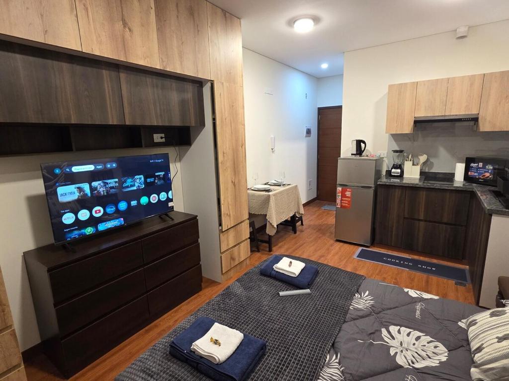 a living room with a large television and a kitchen at Premium 21 Suites in La Paz