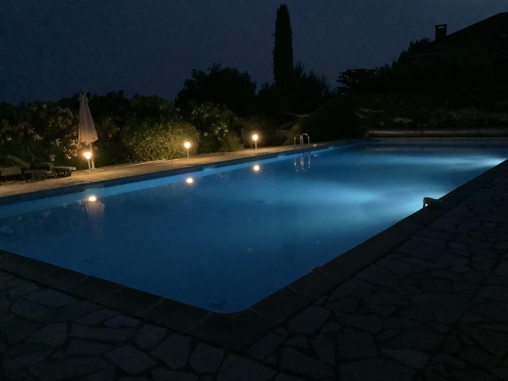 a blue swimming pool at night with lights at Gîte de la Garriguette in Rasteau