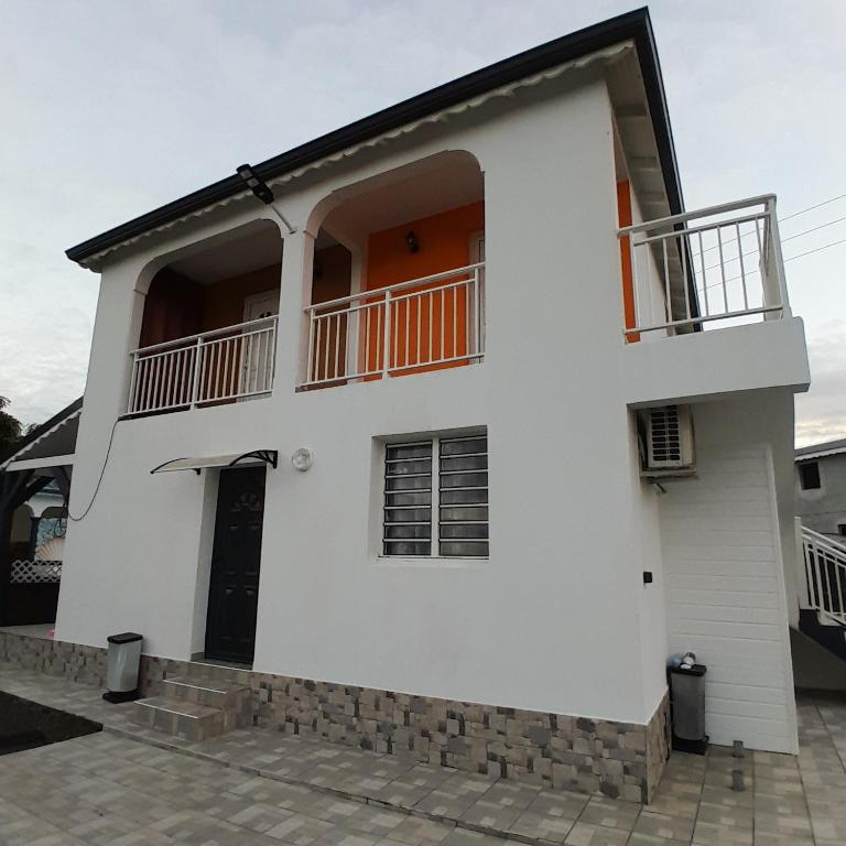 a white house with a balcony at Hébergement Studio Cosy AKOSSOUA in Les Abymes