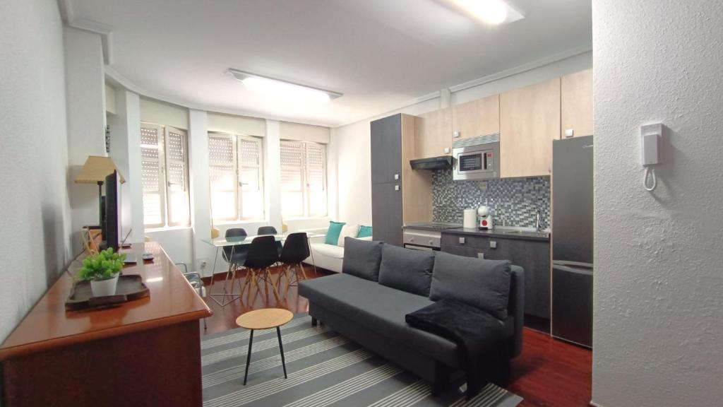 a living room with a couch and a kitchen at Apartamento en Avilés Céntrico & Parking in Avilés