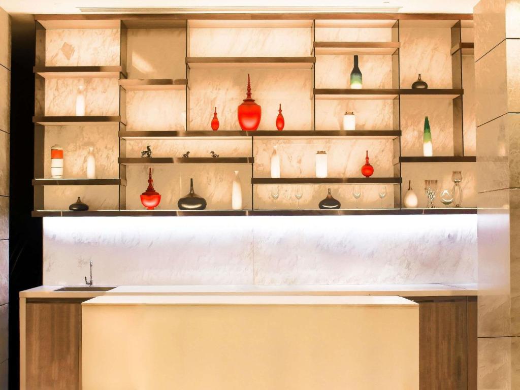 A backlit decorative display of glass vases above a lit counter.