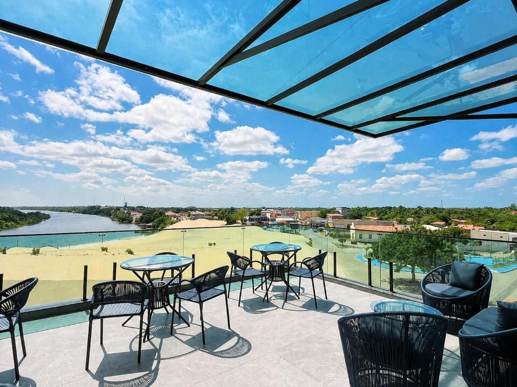 a patio with tables and chairs and a view of a golf course at Bella Vista Hotel in Barreirinhas