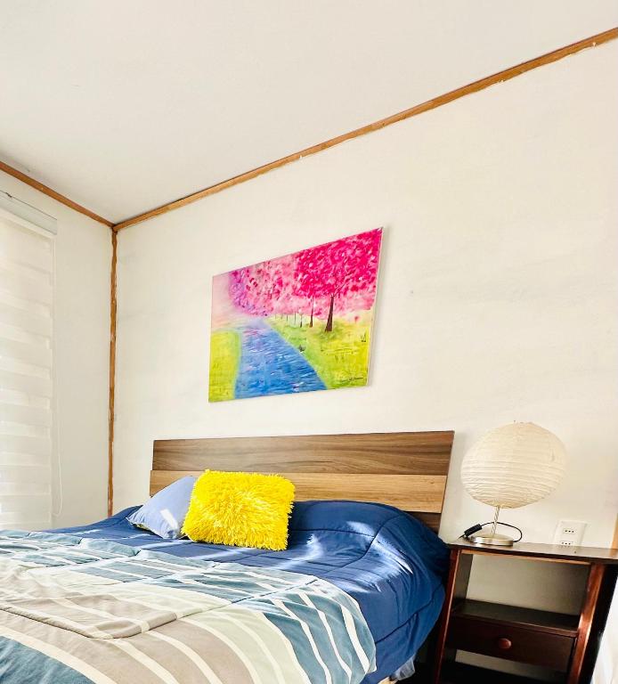 a bedroom with a bed and a painting on the wall at Cabañas buchupureo in Buchupureo