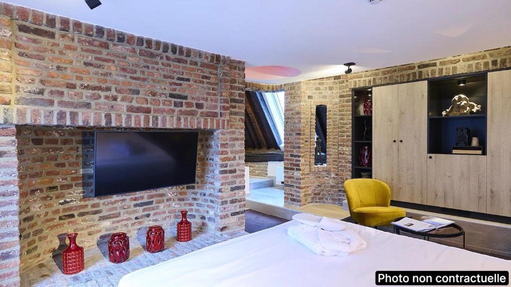 a room with a brick wall with a tv on it at Les Tanneurs in Namur
