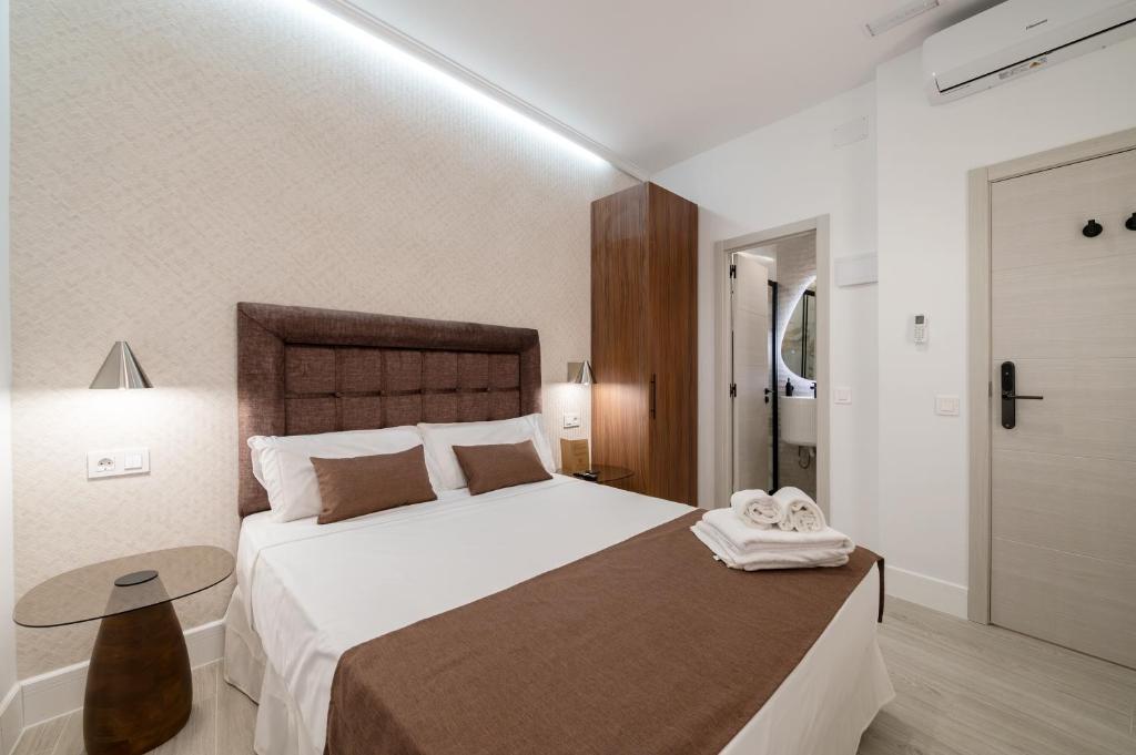 a bedroom with a large white bed and a table at Rosales Suites in Madrid