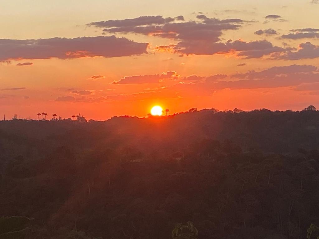 a sunset with the sun setting over the trees at Pousada Cantinho do Dodó in Mulungu
