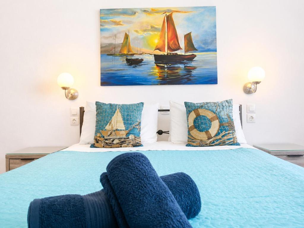 a bedroom with a blue bed with a painting on the wall at Gennadi Sun Apartments 500m from the beach in Gennadi