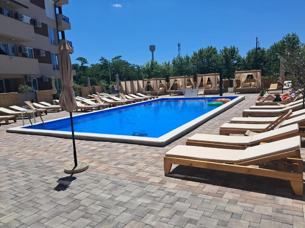 a swimming pool with lounge chairs and an umbrella at Harmony Srebrno jezero in Veliko Gradište