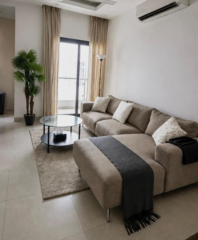 a living room with a couch and a glass table at Cozy Apartment in Boshar in Muscat