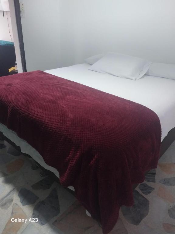 a white bed with a red blanket on it at Alojamiento RUBY'S in Pereira