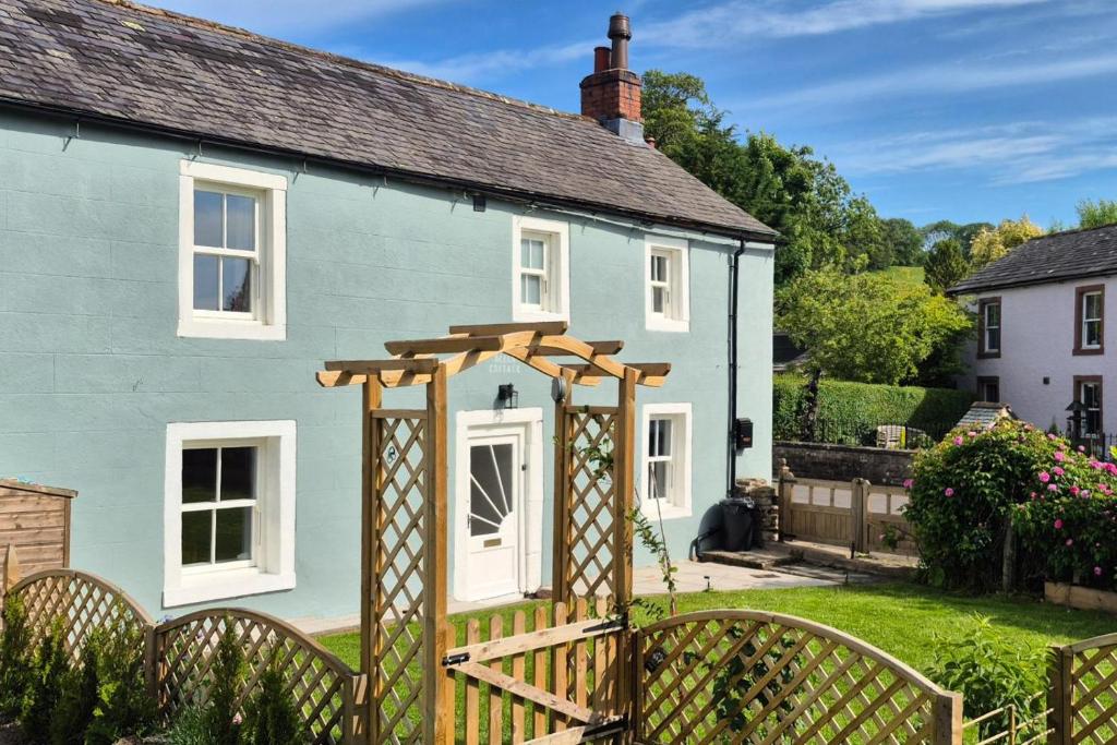 a blue house with a wooden fence in front of it at 2 Bed in Caldbeck oc-b38644 in Caldbeck