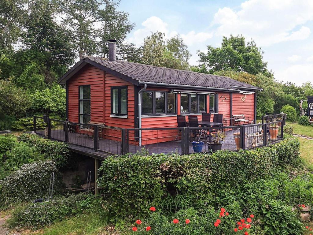 a small red cabin with a porch and a deck at Beautiful cottage near the beach in Vordingborg