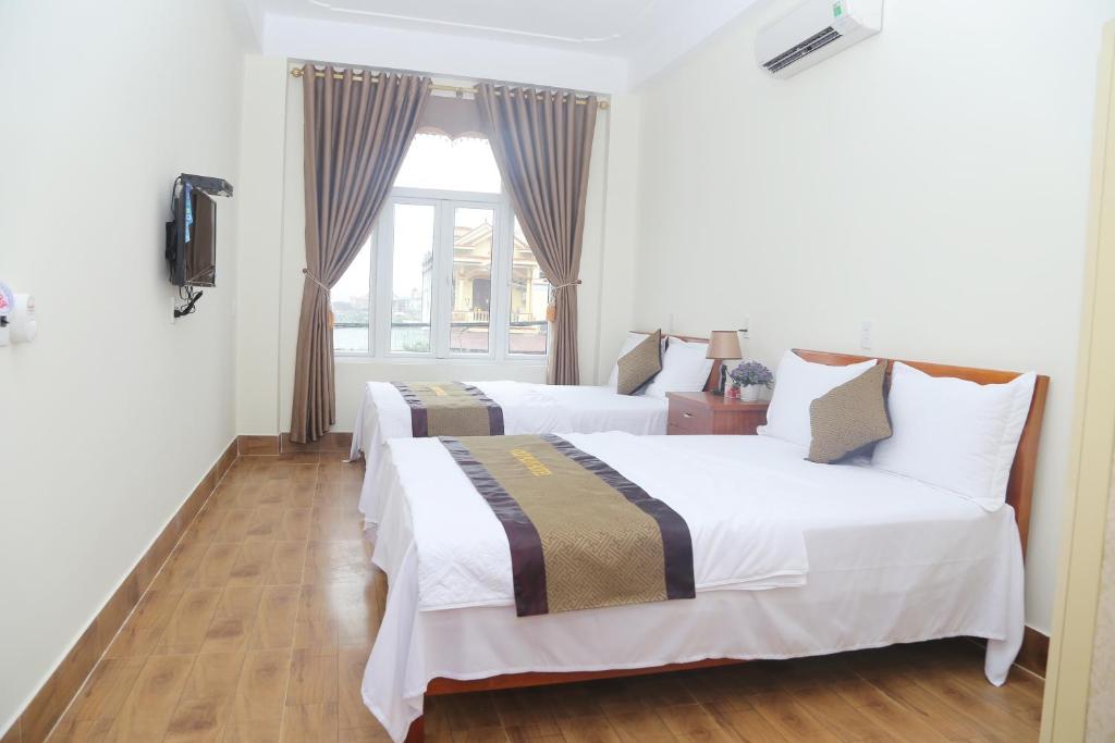 2 Betten in einem Zimmer mit Fenster in der Unterkunft Gold Plus Hotel in Phong Nha