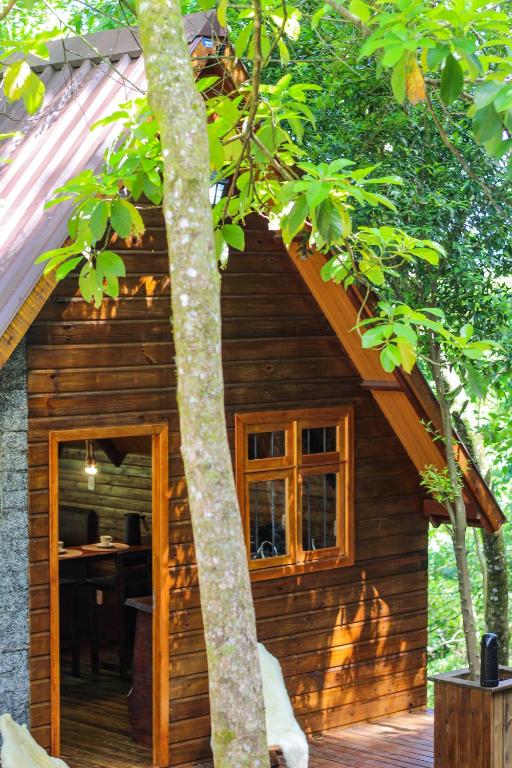 a small wooden cabin with a window and a table at Cabanas do Bosque in Três Coroas