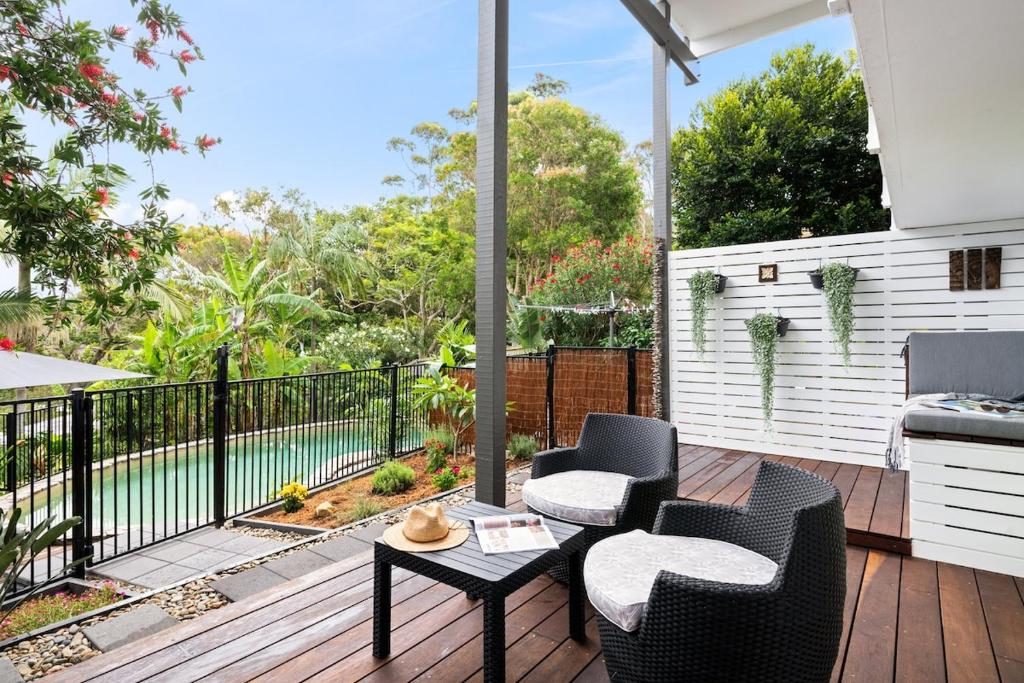 a patio with two chairs and a table on a deck at Green Scape - Whale Beach in Whale Beach