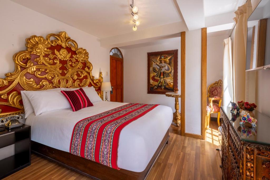 a bedroom with a large bed with a gold headboard at Hotel Monasterio del Inka Cusco in Cusco