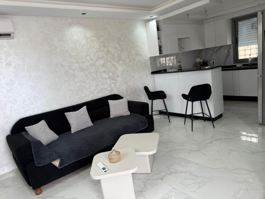 a living room with a black couch and a kitchen at Villa neuve avec une grande terrasse in Dar Tahar Zaouch