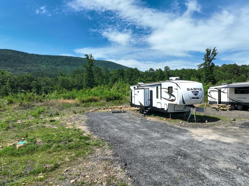two rvs parked on the side of a dirt road at Ouachita Outpost RV Park in Hodgen