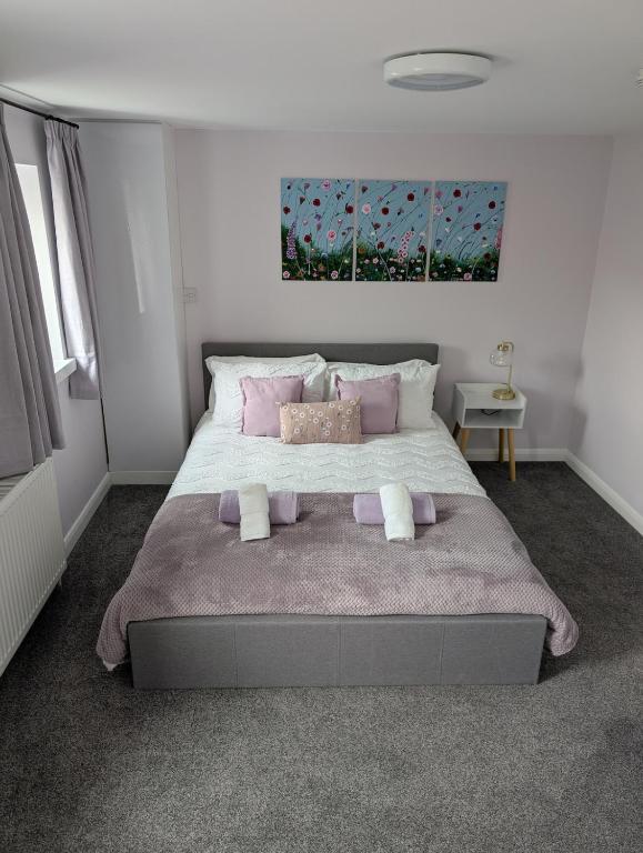 a bedroom with a large bed with pink pillows at Stylish town flat in Bude, with secure parking in Bude