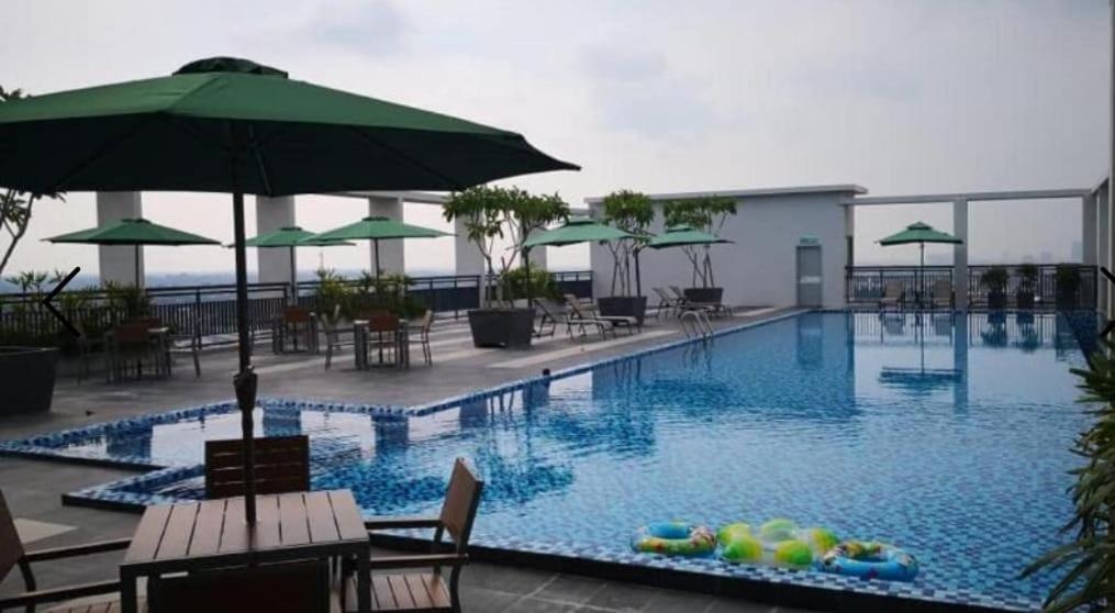 a large swimming pool with chairs and an umbrella at SF Roomstay Tunjong in Kota Bharu